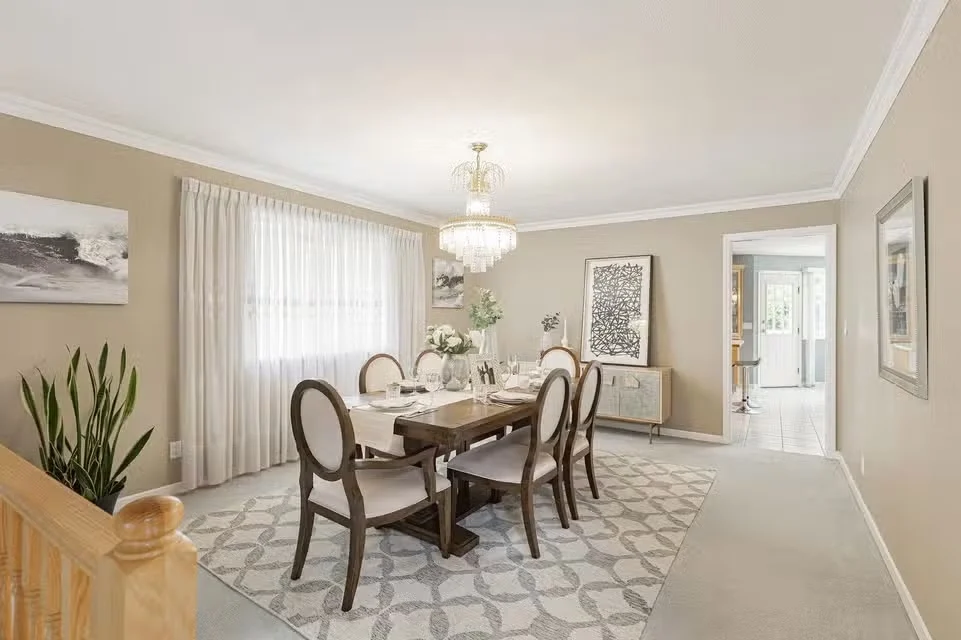 The same dining room staged with a lighter table, upholstered chairs and artwork